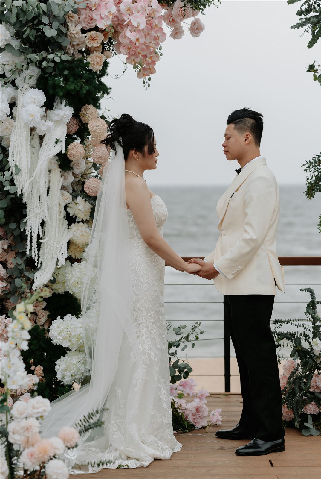 Thuỳ Tiên và Tuấn Vũ nắm tay dưới cổng hoa bên biển
